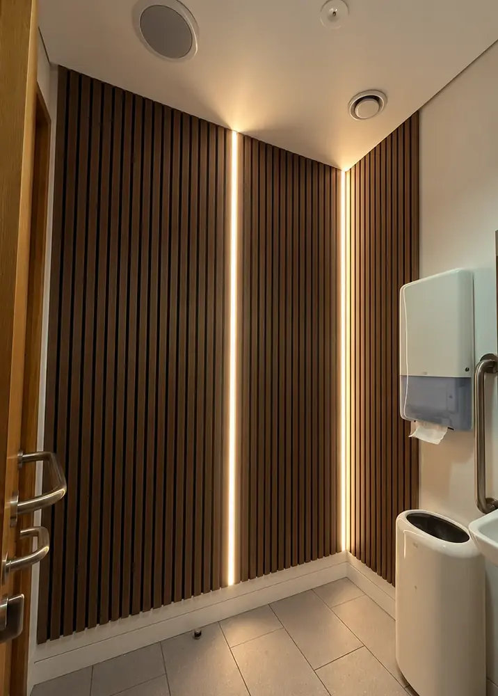 The same corner with timber slat panelling and two vertical lines of warm LED light